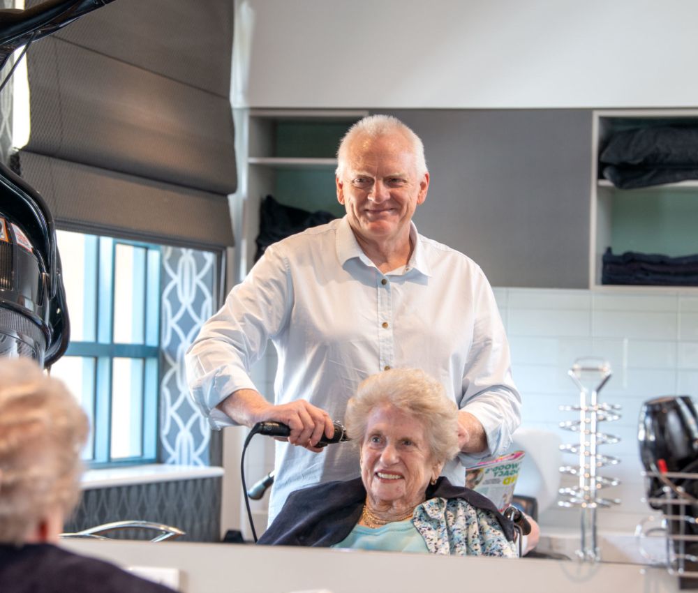 A hairdresser styles an Eldercare resident's hair in the on-site hairdressing salon.
