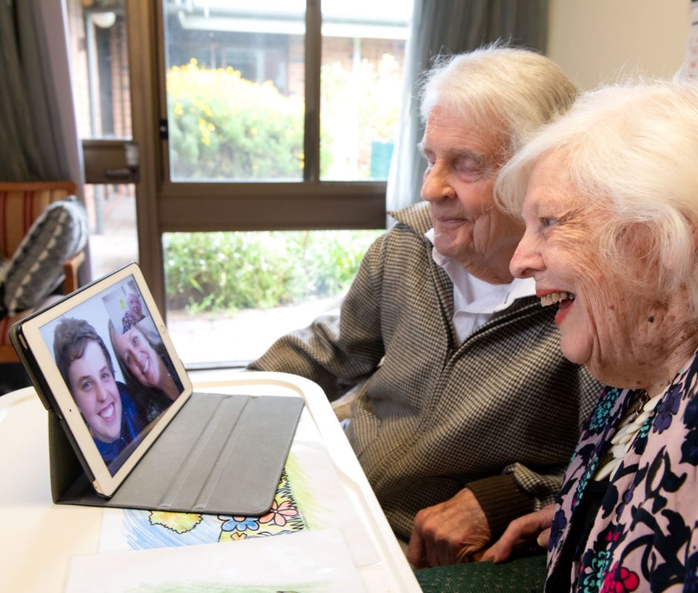 Eldercare Sash Ferguson residents smiling at an iPad while FaceTiming two family members.