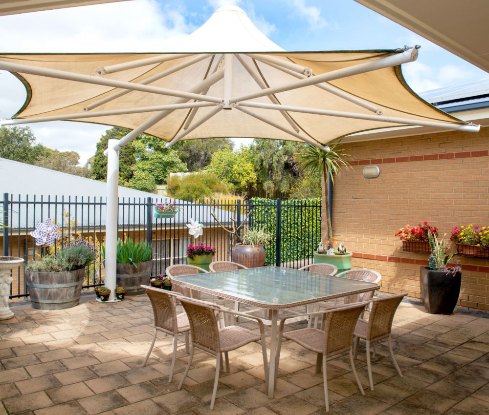 Eldercare Cottage Grove outdoor area with dining set and umbrella.
