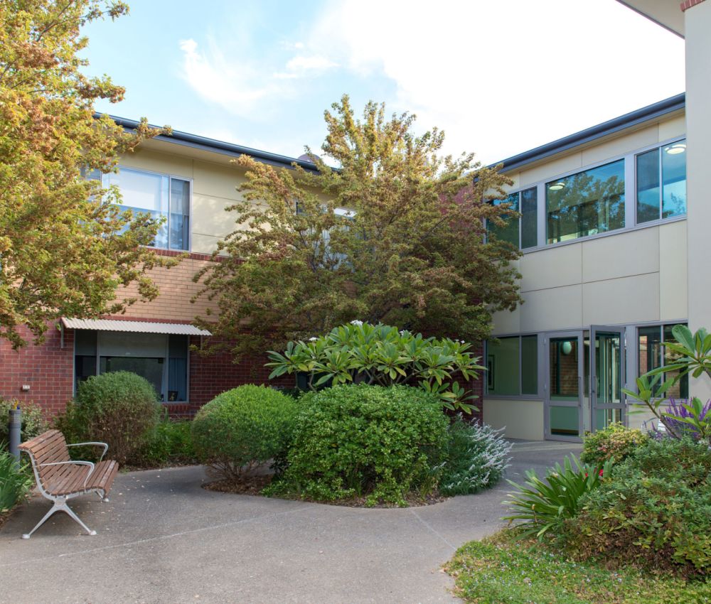 Courtyard at Eldercare Seaford complete with park bench and green trees and shrubbery.