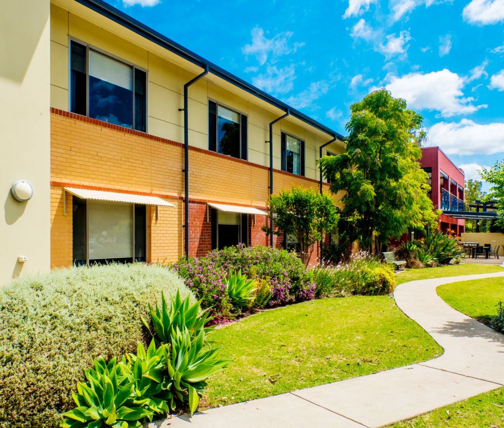 Eldercare Seaford's front garden area, featuring a path, against a blue sky with fluffy clouds.