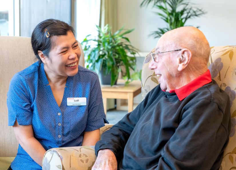 An Eldercare carer and a resident smiling at each other.