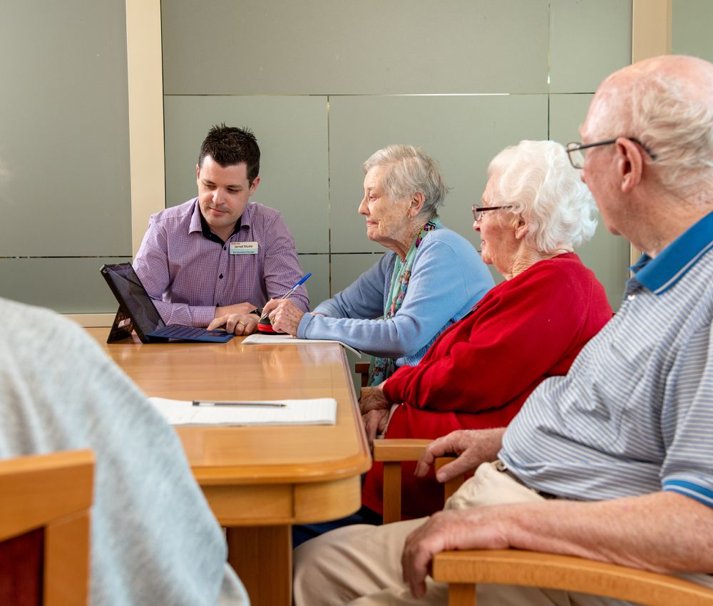 Eldercare General Manager Residential Care Jarrod Mudie with Eldercare Seaford residents and a family member in a meeting.
