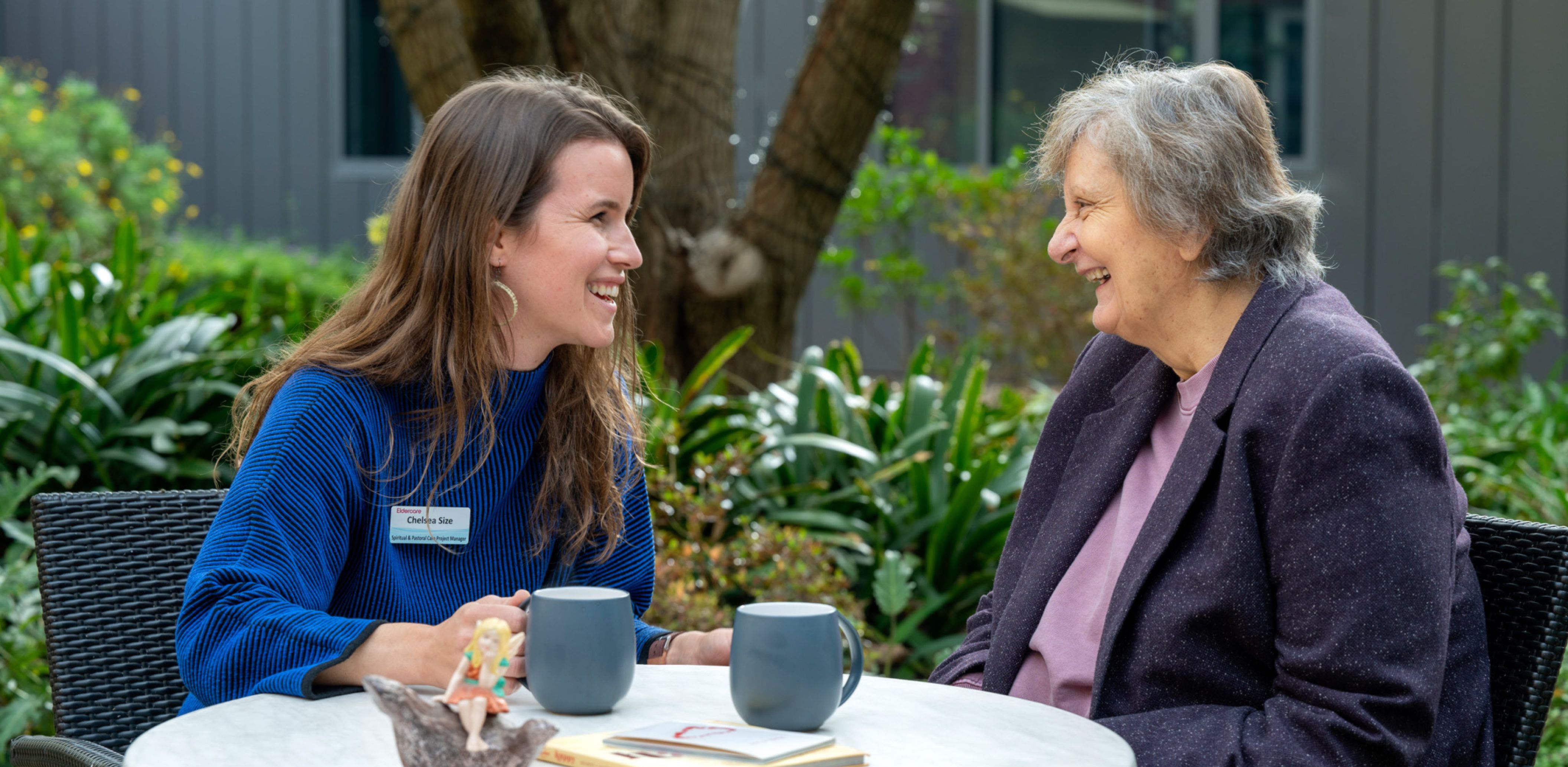 Eldercare staff member chatting with a resident over coffee