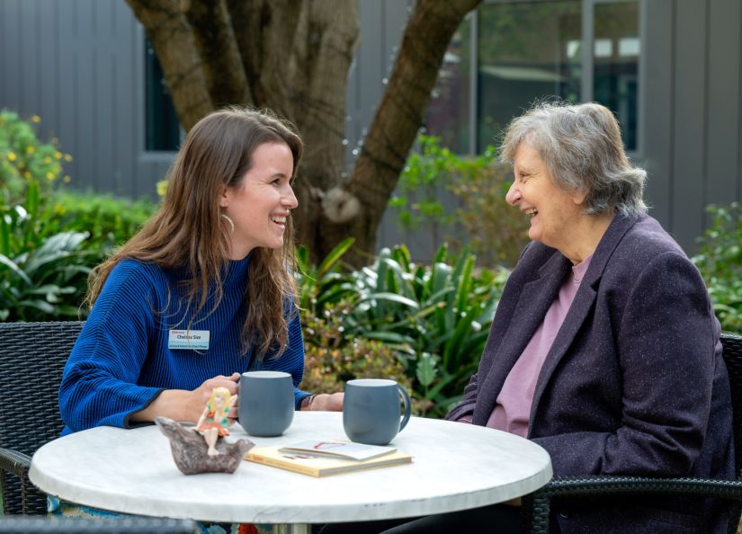 Eldercare staff member chatting with a resident over coffee