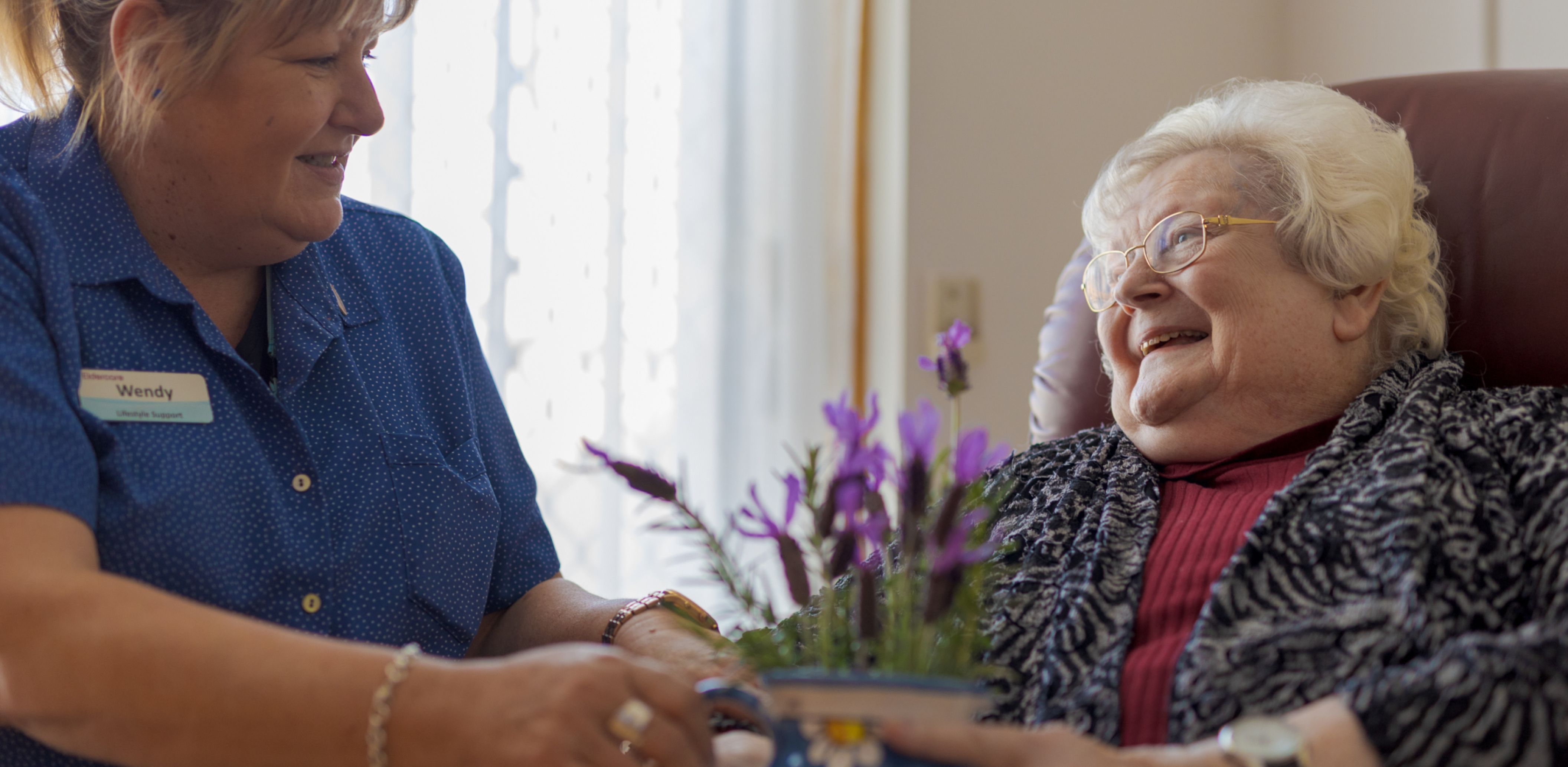 An Eldercare lifestyle support staff member gives a resident a pot filled with lavender.