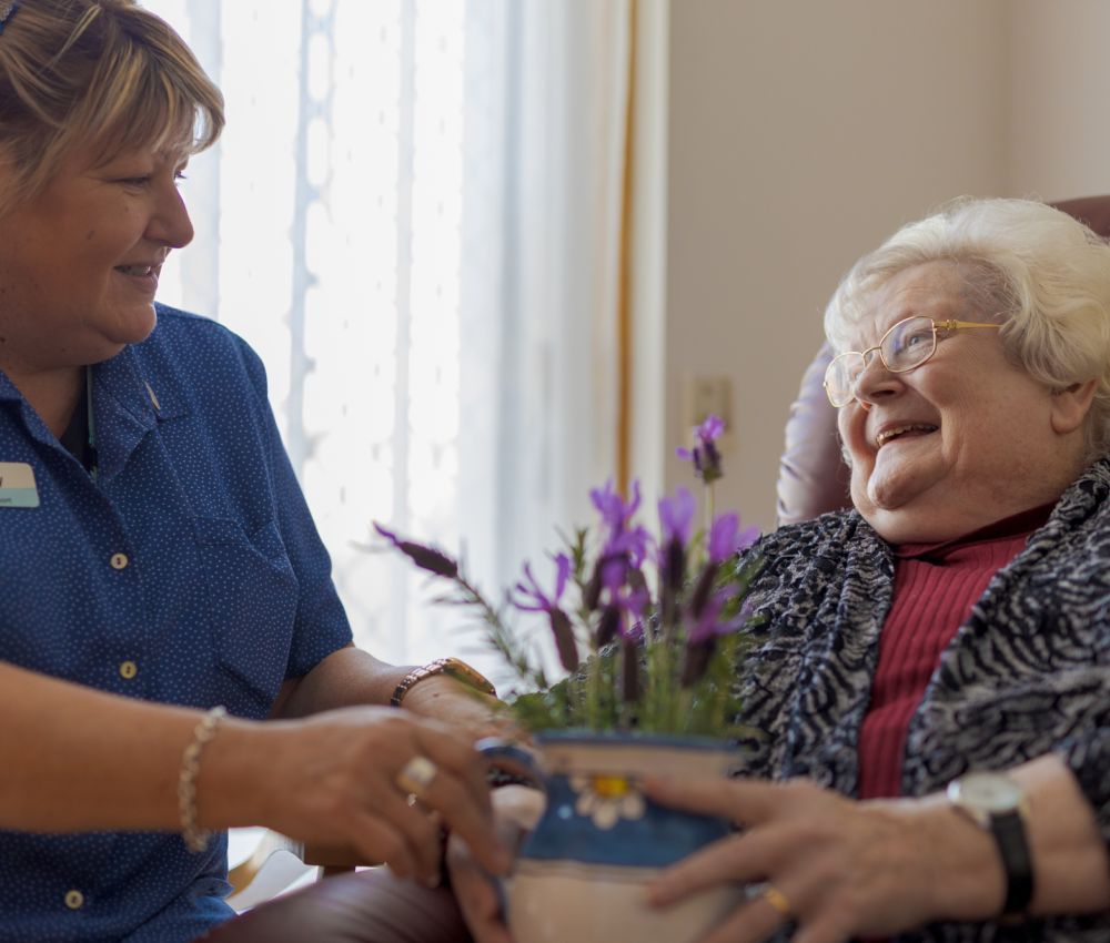 An Eldercare lifestyle support staff member gives a resident a pot filled with lavender.