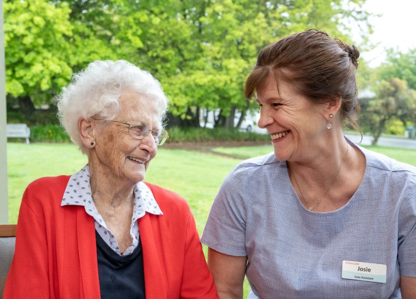 An Eldercare Care Assistant and a resident smiling at each other.