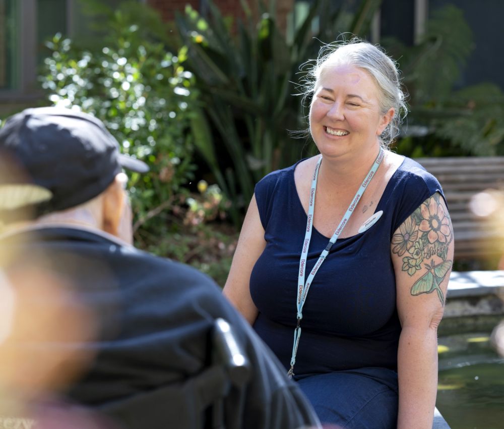Eldercare volunteer talking to two residents.