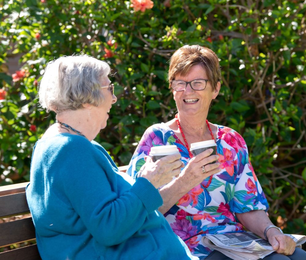 Eldercare Mulberry Grove Retirement Living residents drinking coffee and smiling at each other.