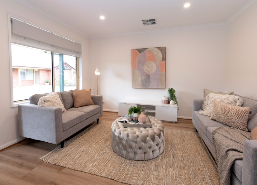A modern living room showcasing a soft couch and a ottoman for a stylish atmosphere.